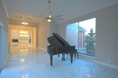 Real Estate Photo - Entertainment area of a house with a grand piano and a large window.