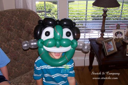 Green balloon twisting Frankenstein monster mask worn by kid at party