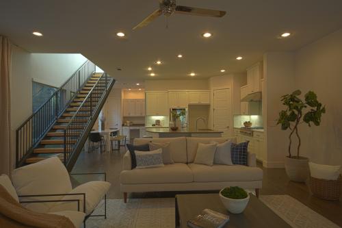 Real Estate Photo - Town house living room with kitchen in background and stairs on the left.